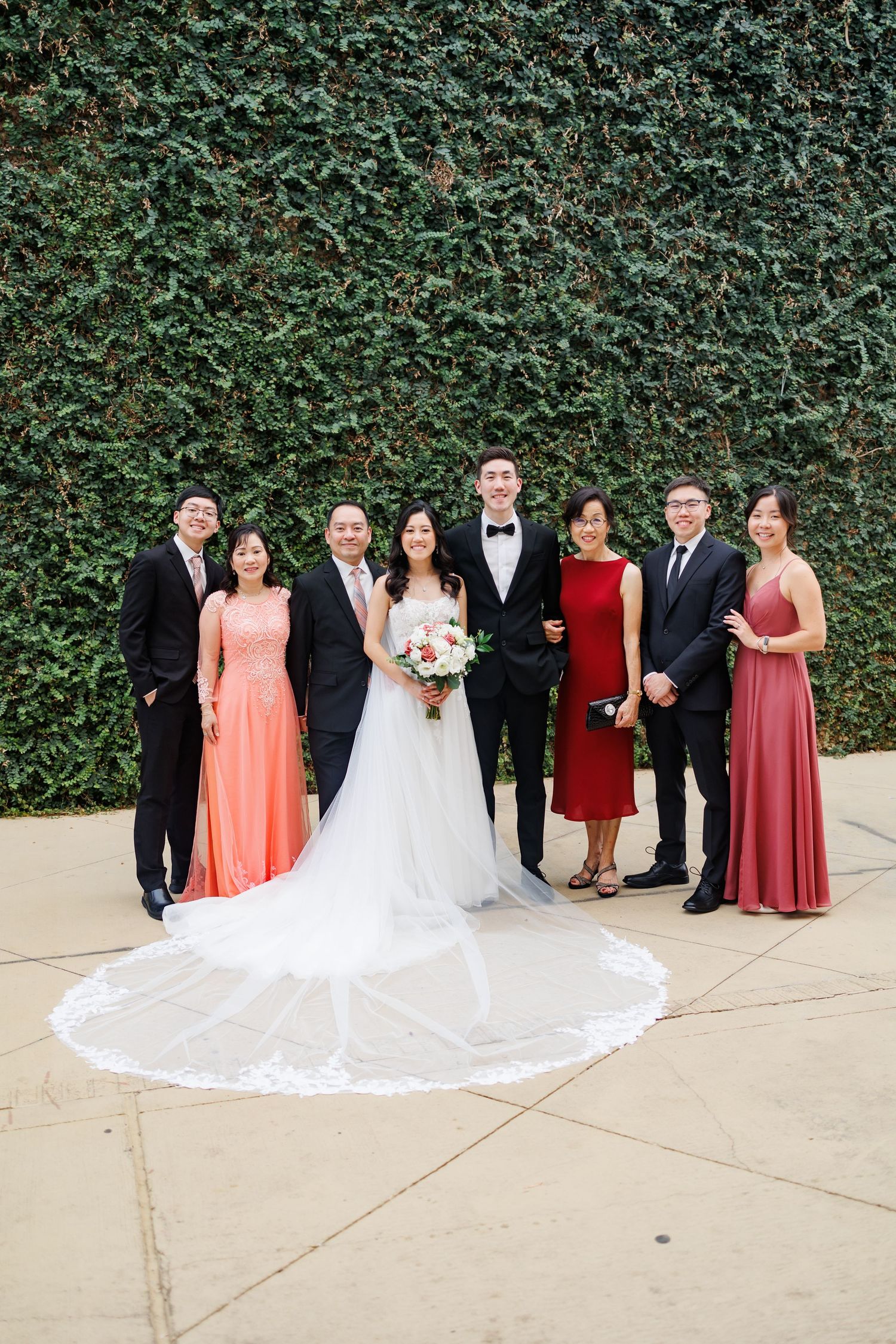 Bride and groom posing with their parents for a group wedding photo outside
