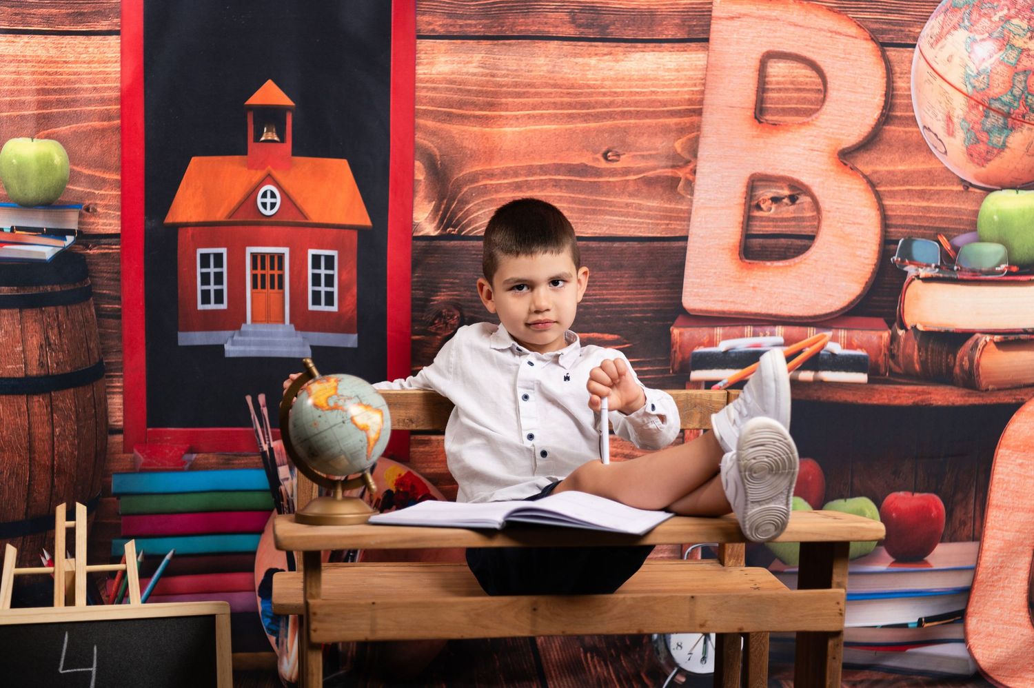 Educational themed photography setup with schoolhouse backdrop and learning materials.