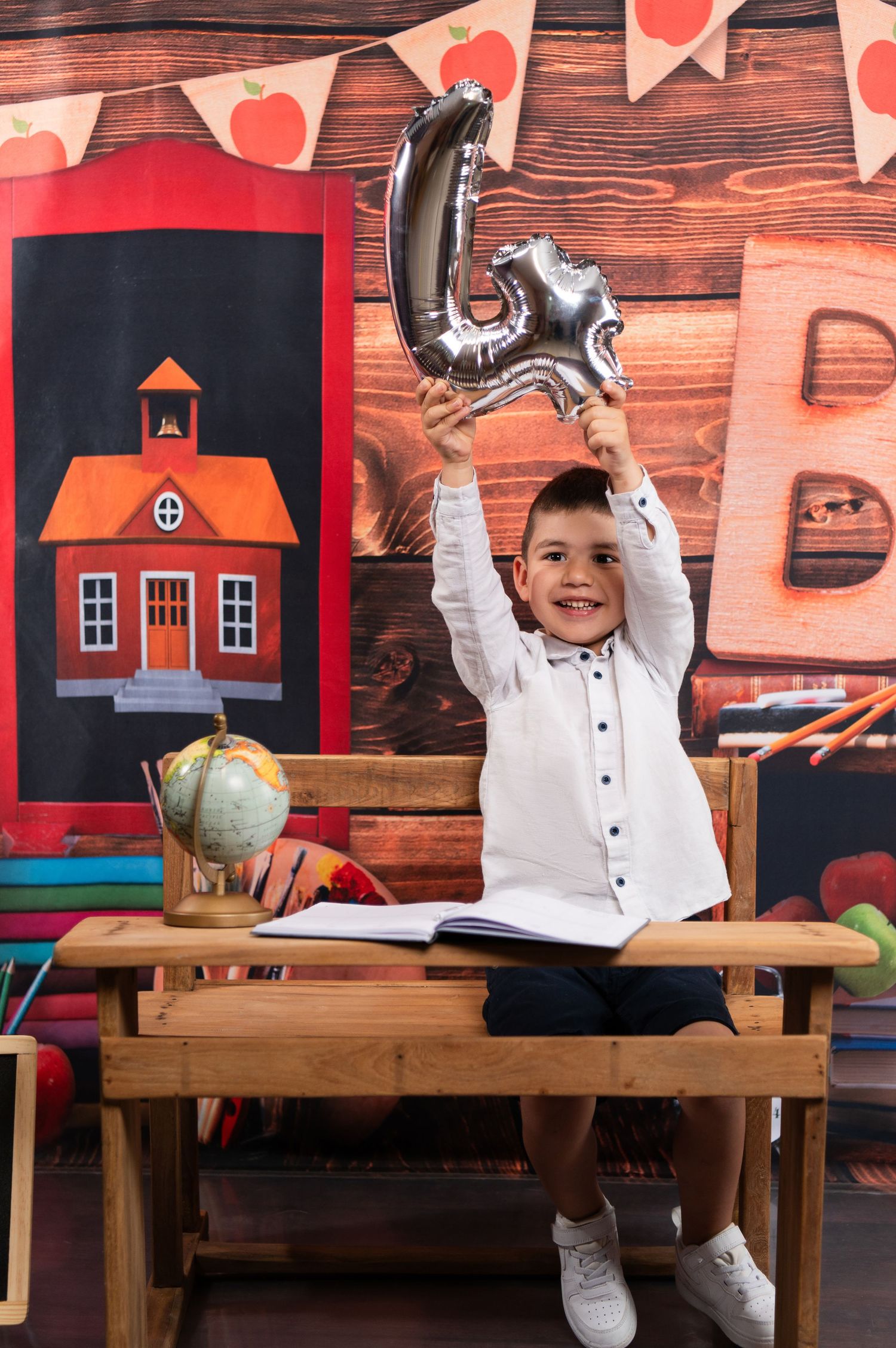 Child at school desk with heart banner decorations and wooden wall background.
