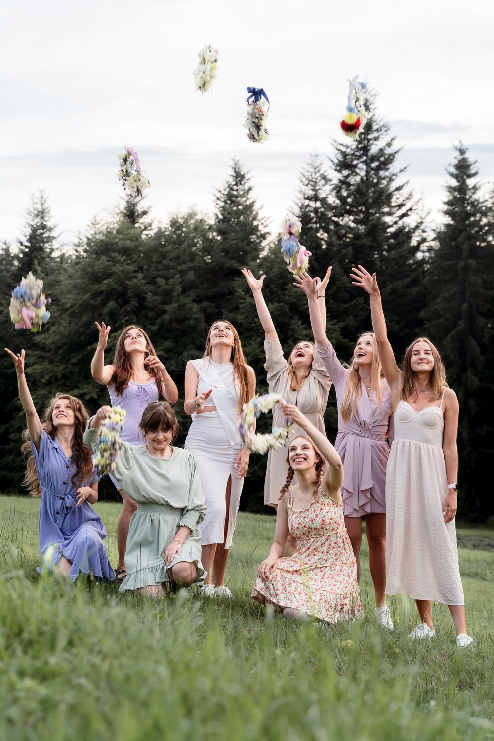 Boho sesja wieczoru panieńskiego w Beskidach, przyjaciółki podrzucają wianki w lesie, naturalne i pełne emocji ujęcia.