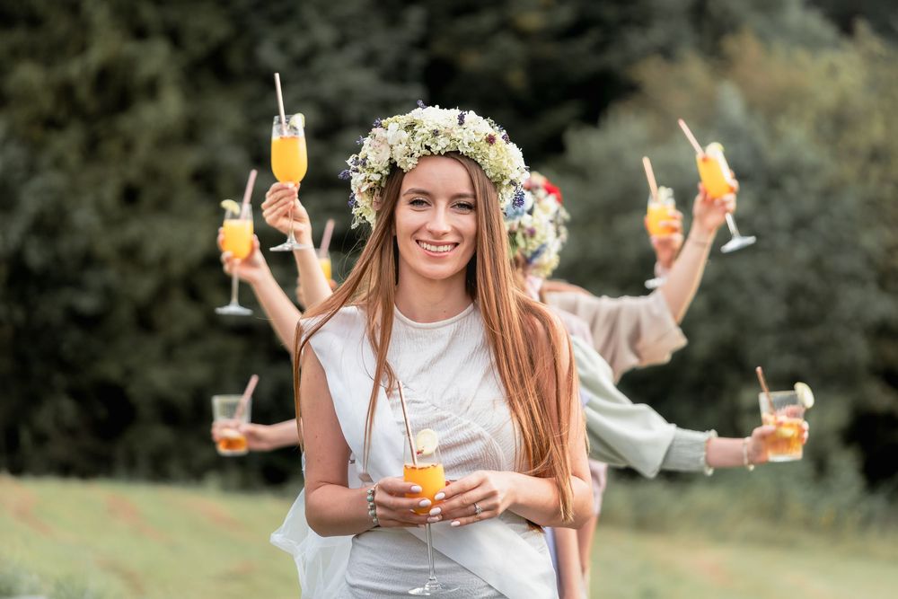 Przyjaciółki pozują z drinkami podczas sesji wieczoru panieńskiego w Beskidach, Dobra, sesja w boho stylu, spontaniczna i radosna.