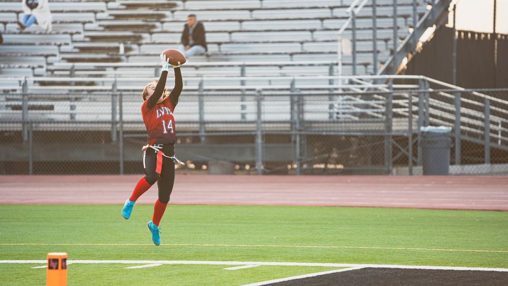 Girls flag football player making a jump catch