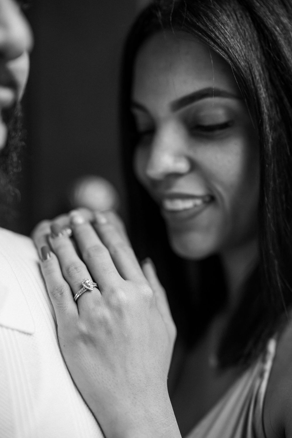 Black and white portrait showing emotion through body language with subtle smile and ring on hand.