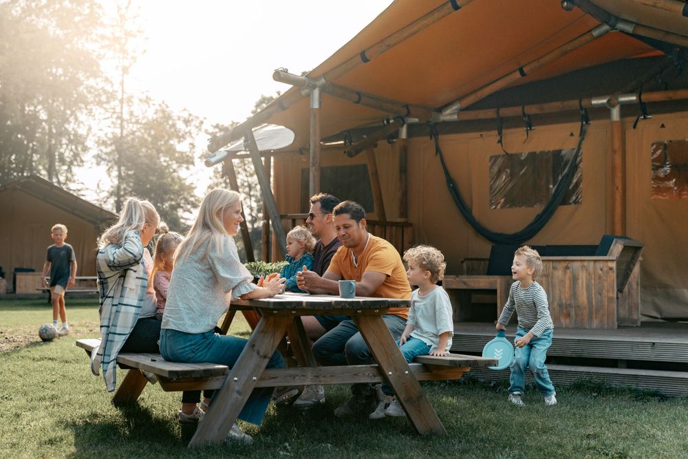 Group of friends relaxing on blankets under an awning at sunset.