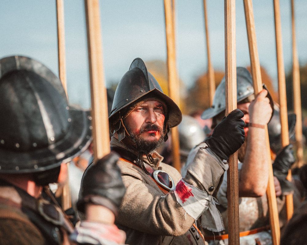 Medieval reenactors lined up with spears against a blurred background.