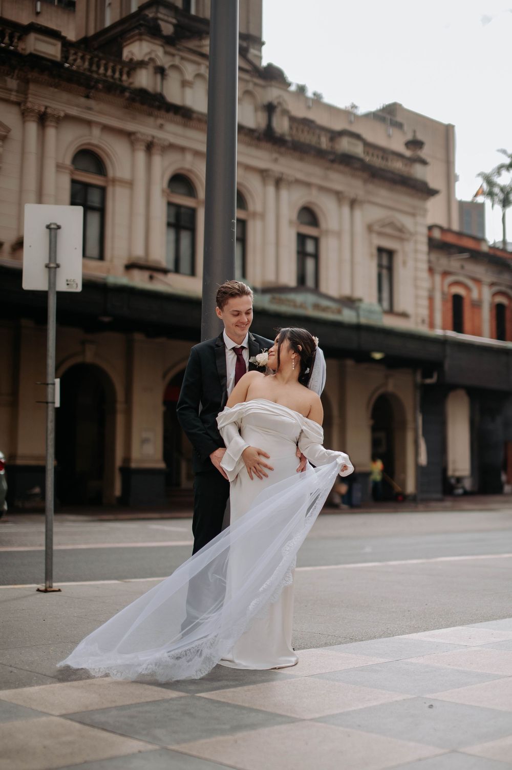 A series of wedding photos showing a couple dancing on a city street with a flowing white veil in motion.