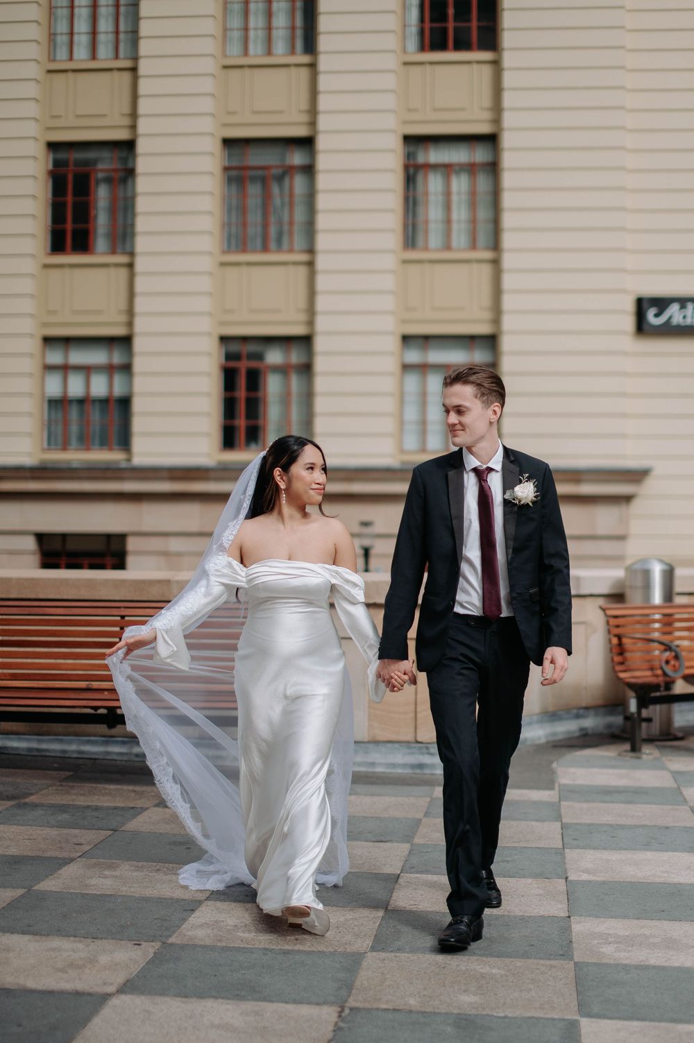 A sequence of wedding photos shows a bride's wedding dress flowing in the wind as she walks with a groom on stone pavement.