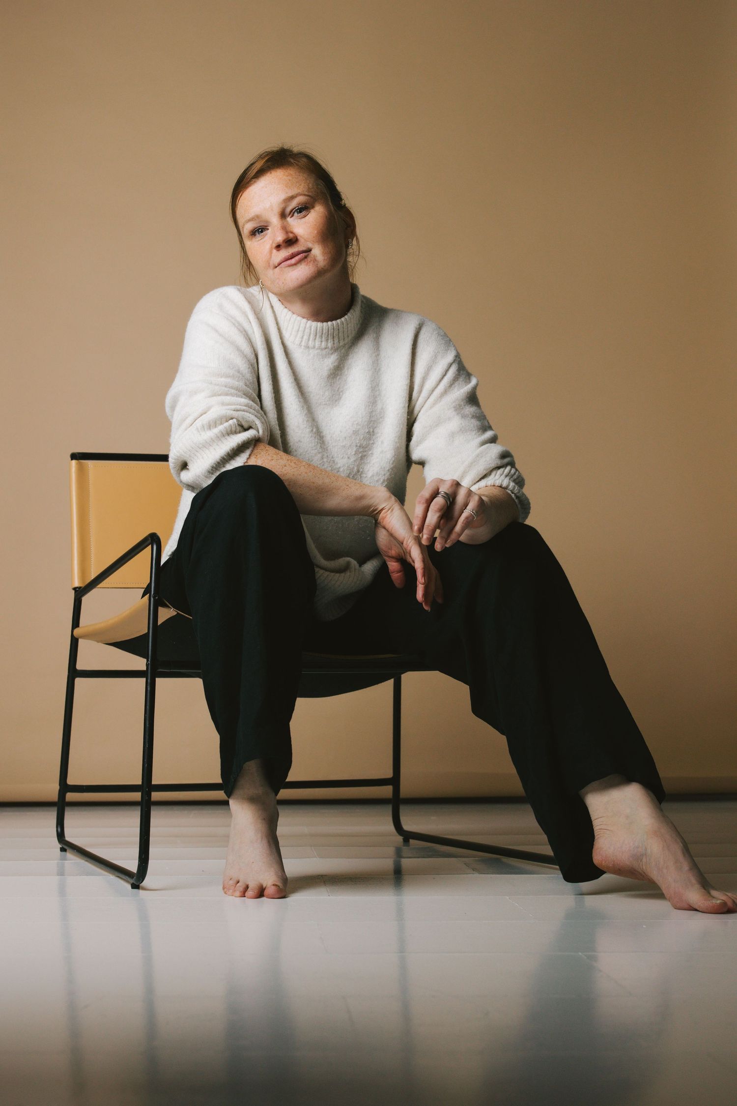 Valokuvaaja Annina Nygård istuu valokuvausstudiolla, ruska taustakangas. Kuvan on ottanut Marissa Tammisalo.