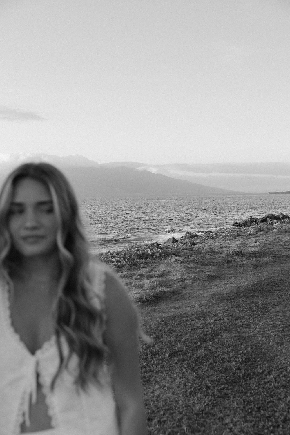 Scenic black and white coastal landscape with grassy hills overlooking a misty ocean horizon.