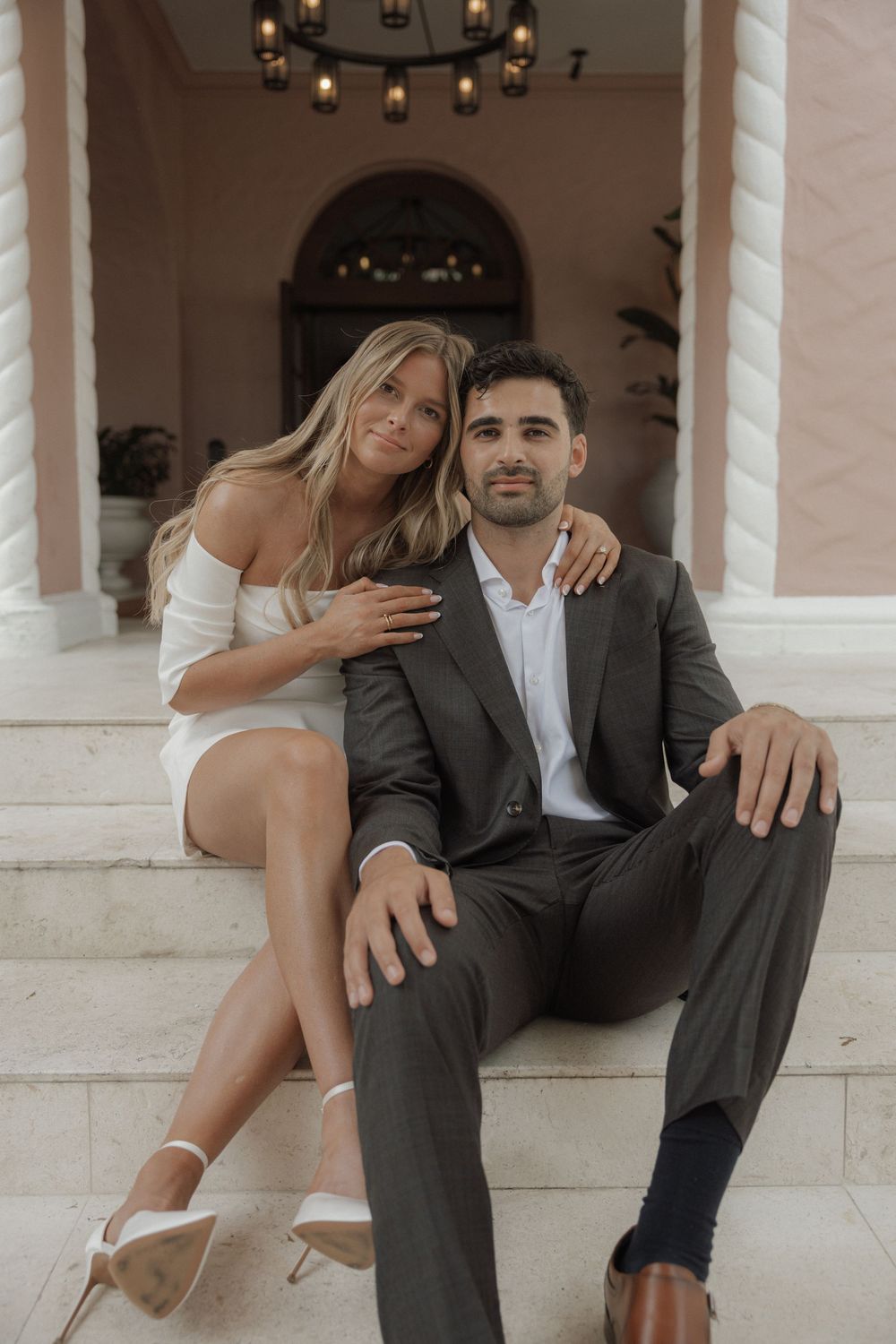 Artistic fashion photoshoot on white marble steps with contrasting formal and casual styling.