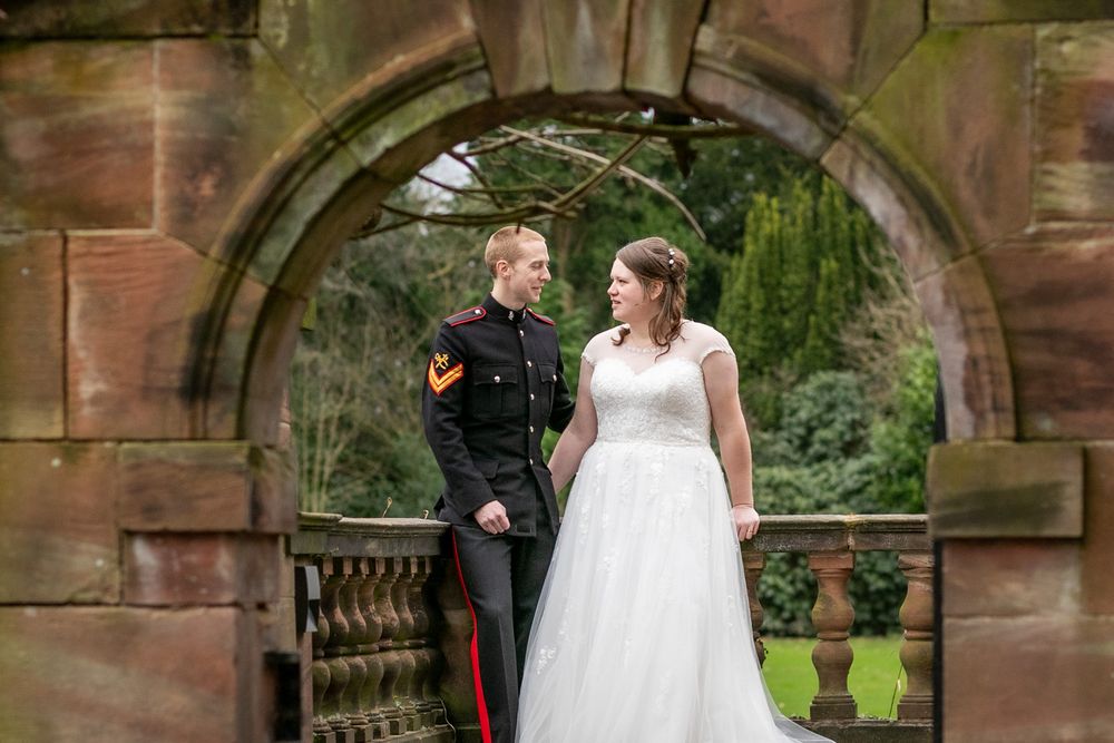 Candid wedding portrait of a couple through an arch at Inglewood Manor, Cheshire. Bright, colourful wedding photography.
