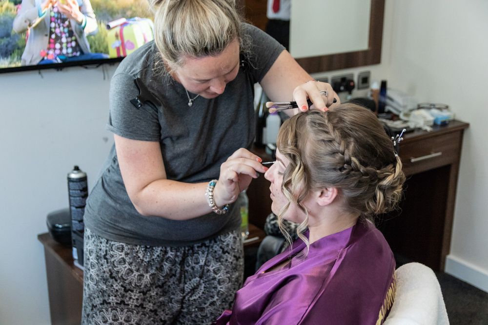 A bridesmaid and makeup artist during prep on the morning of a wedding day. Denbighshire Wedding Photography.