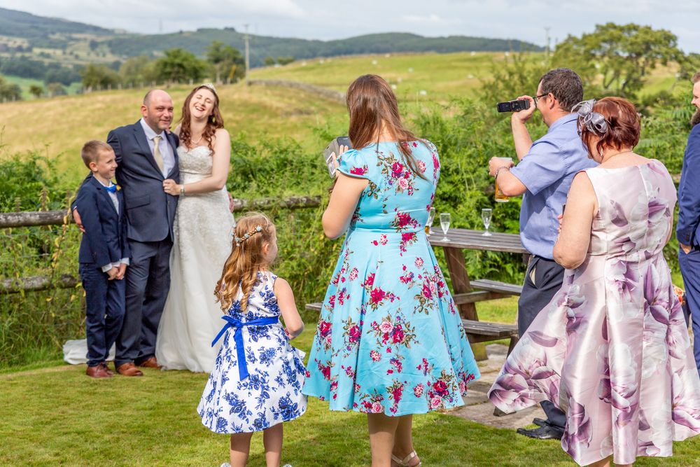Guests taking pictures of the bride and groom at the wedding drinks reception. Bright, colourful wedding photography.