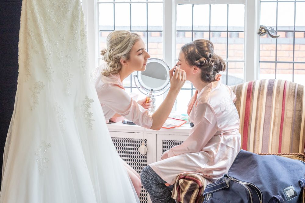 2 bridesmaids sorting their makeup during prep at MacDonald Craxton Wood. Bright, colourful wedding photography.