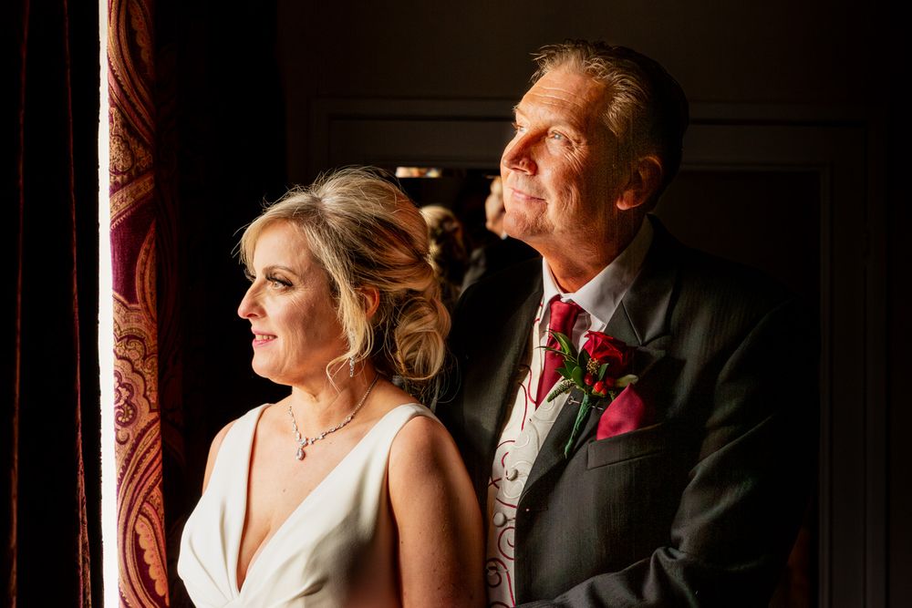 A dramatic portrait of a bride and groom lit by the light from a window at MacDonald Craxton Wood, North Wales.