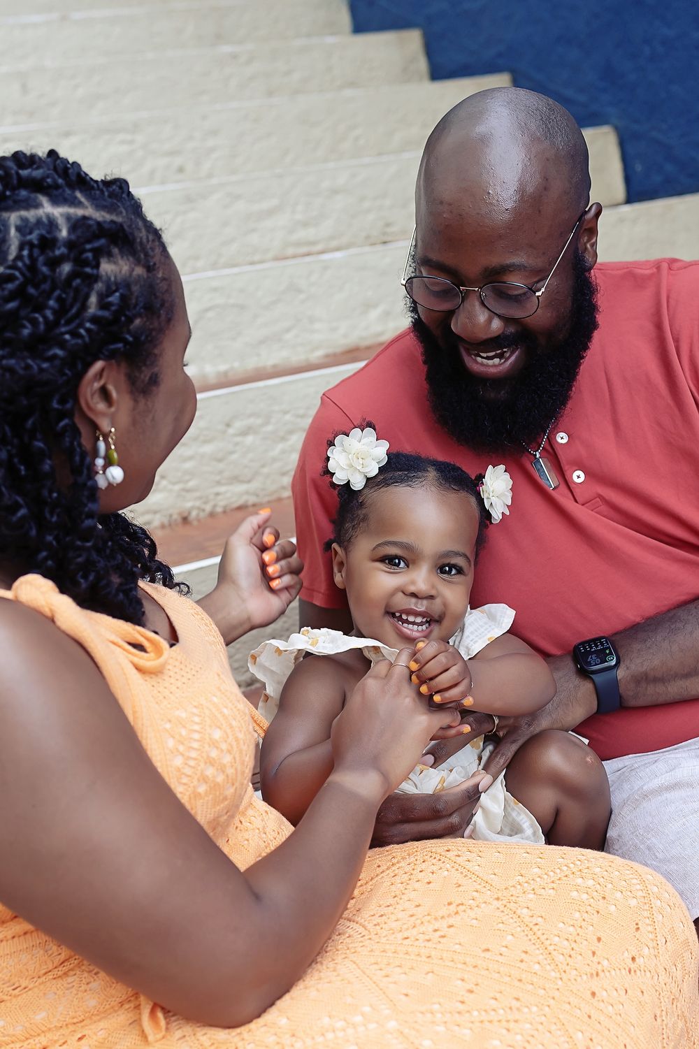 Three family members share a joyful moment together while sitting and smiling during an outdoor gathering.