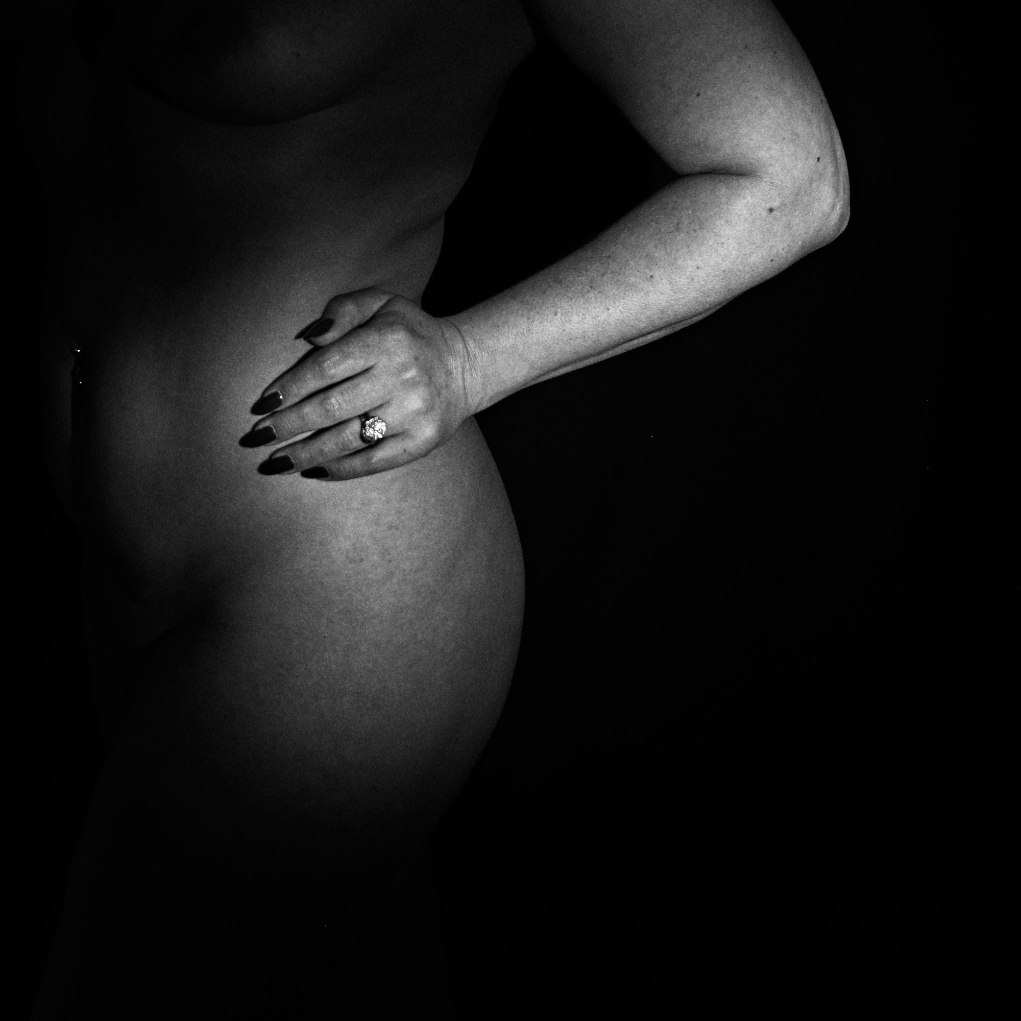 Black and white image of a woman's torso in a white vest. Boudoir photography making her feel empowered.