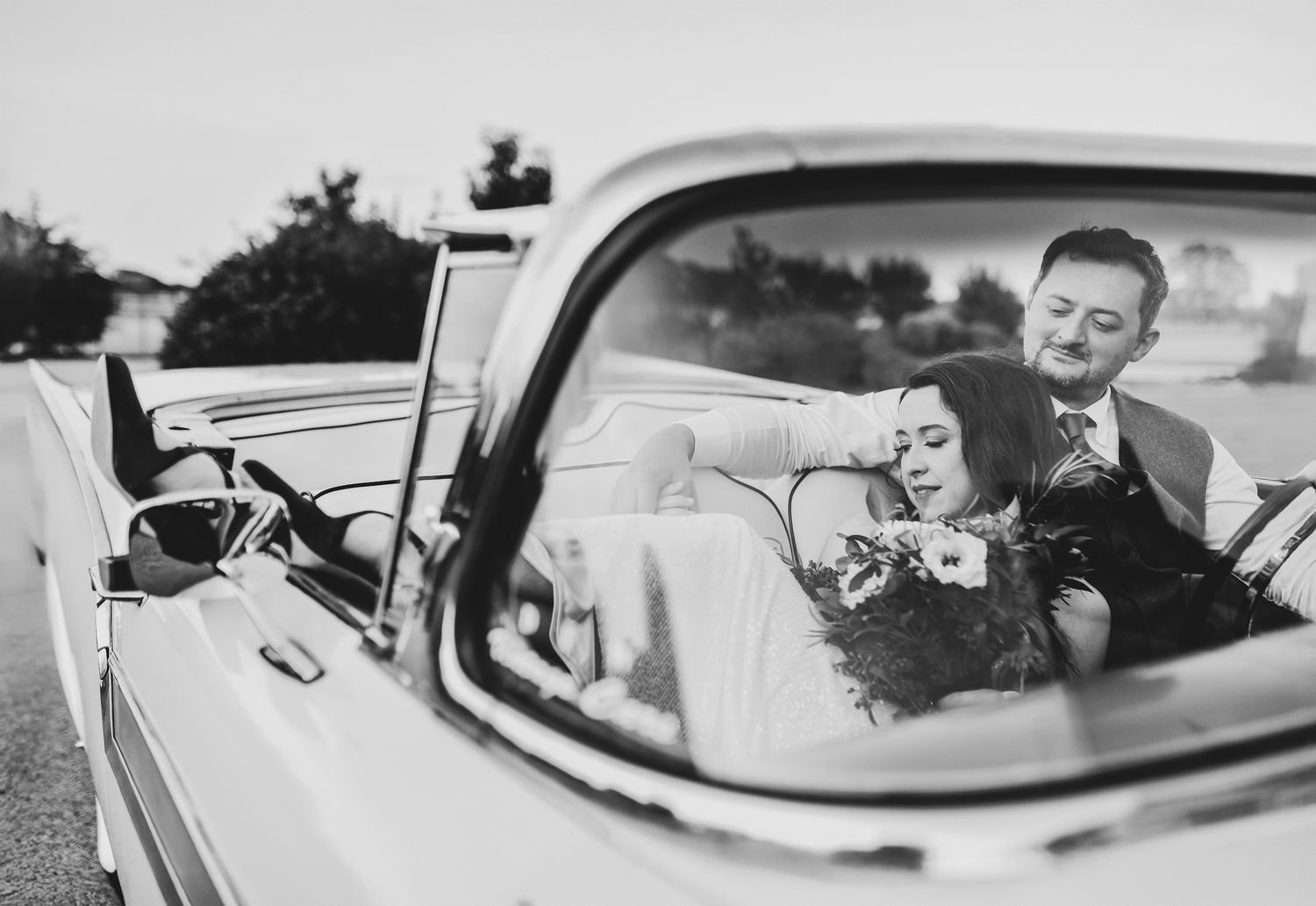 Bride and groom lounge in their rented vintage car to celebrate their wedding at the Oak & Ivy Wedding Venue