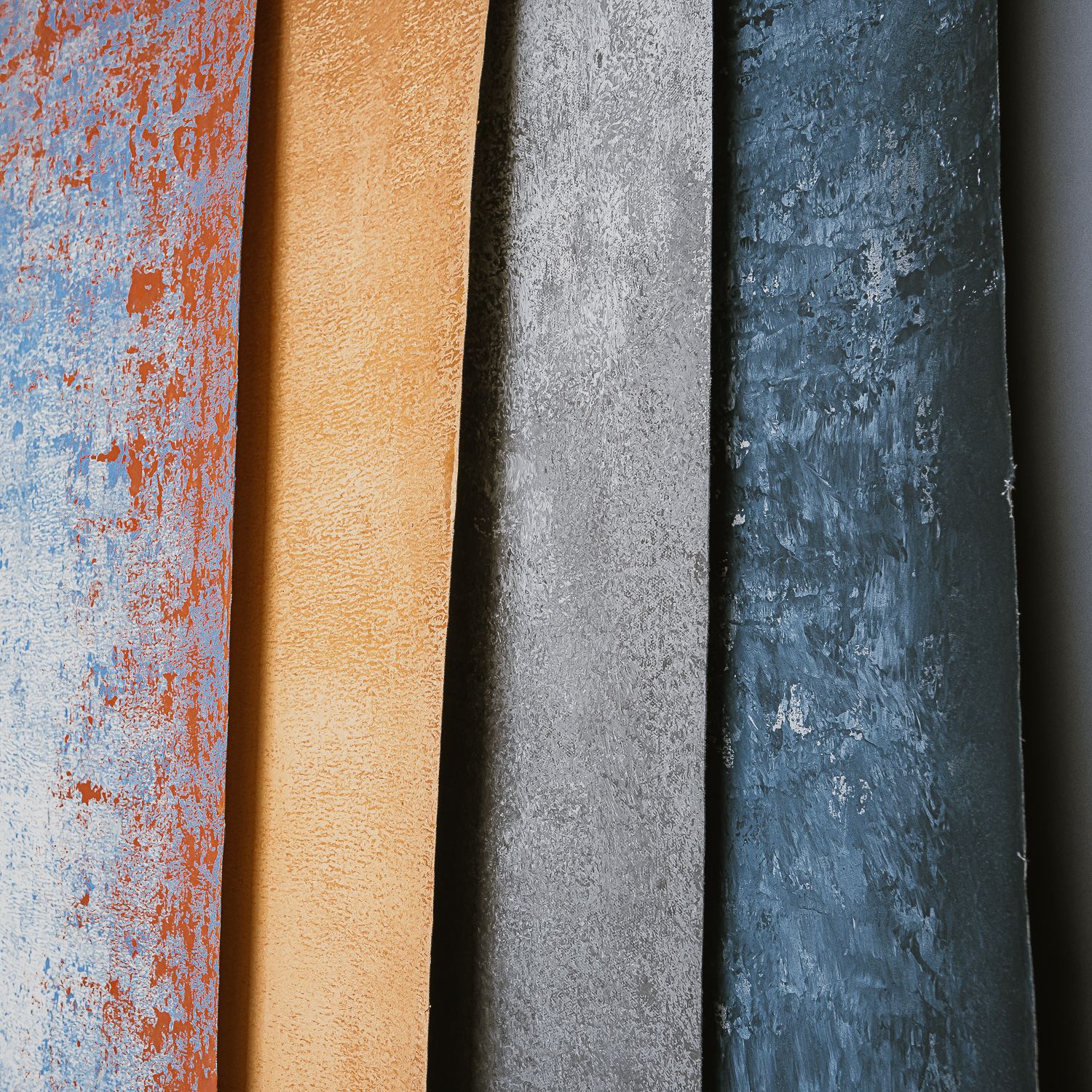 Macro view of old books arranged vertically showing weathered spines in shades of orange, tan, gray and blue.
