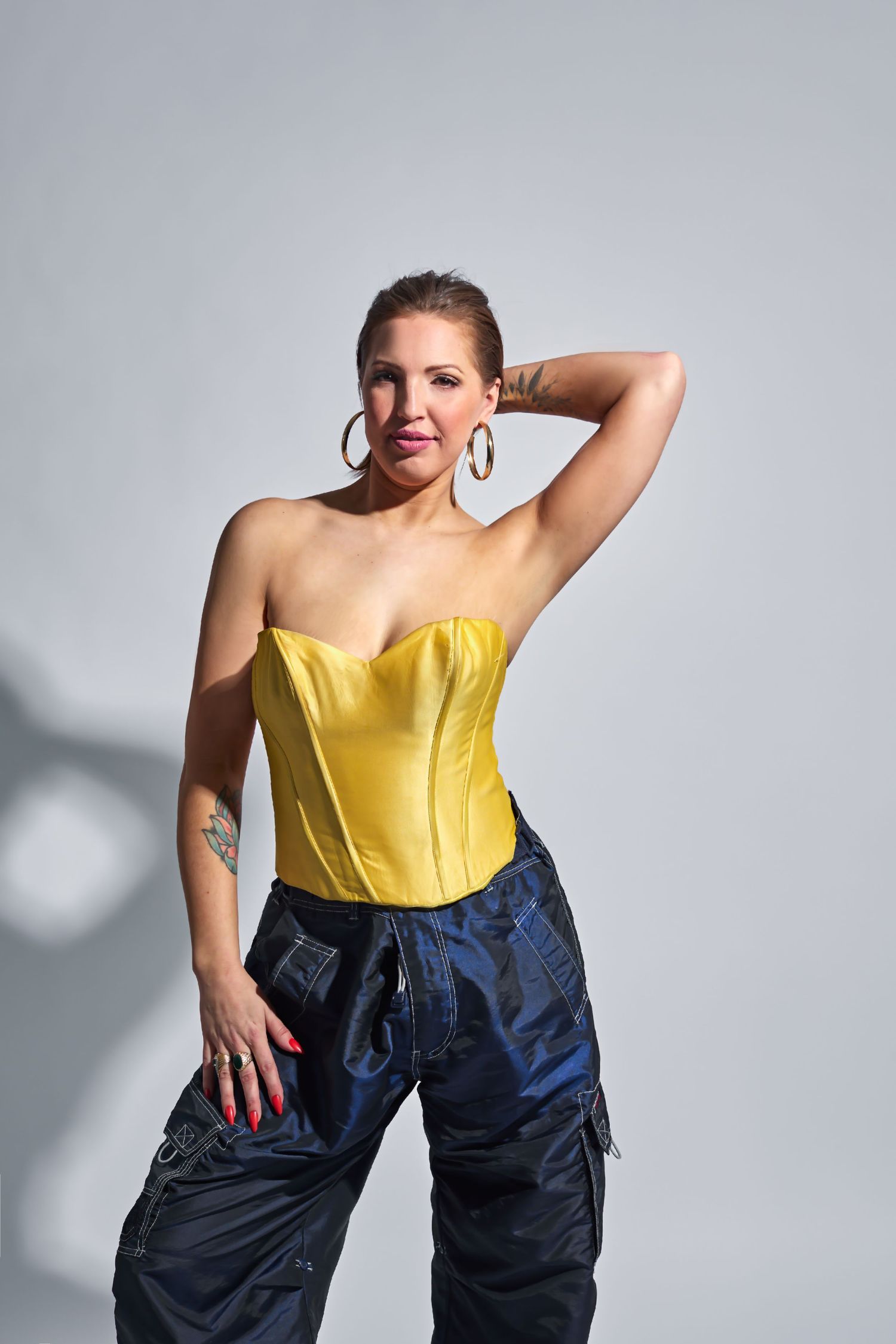 Fashion photo sequence featuring a yellow corset top and navy cargo pants against a gray backdrop.