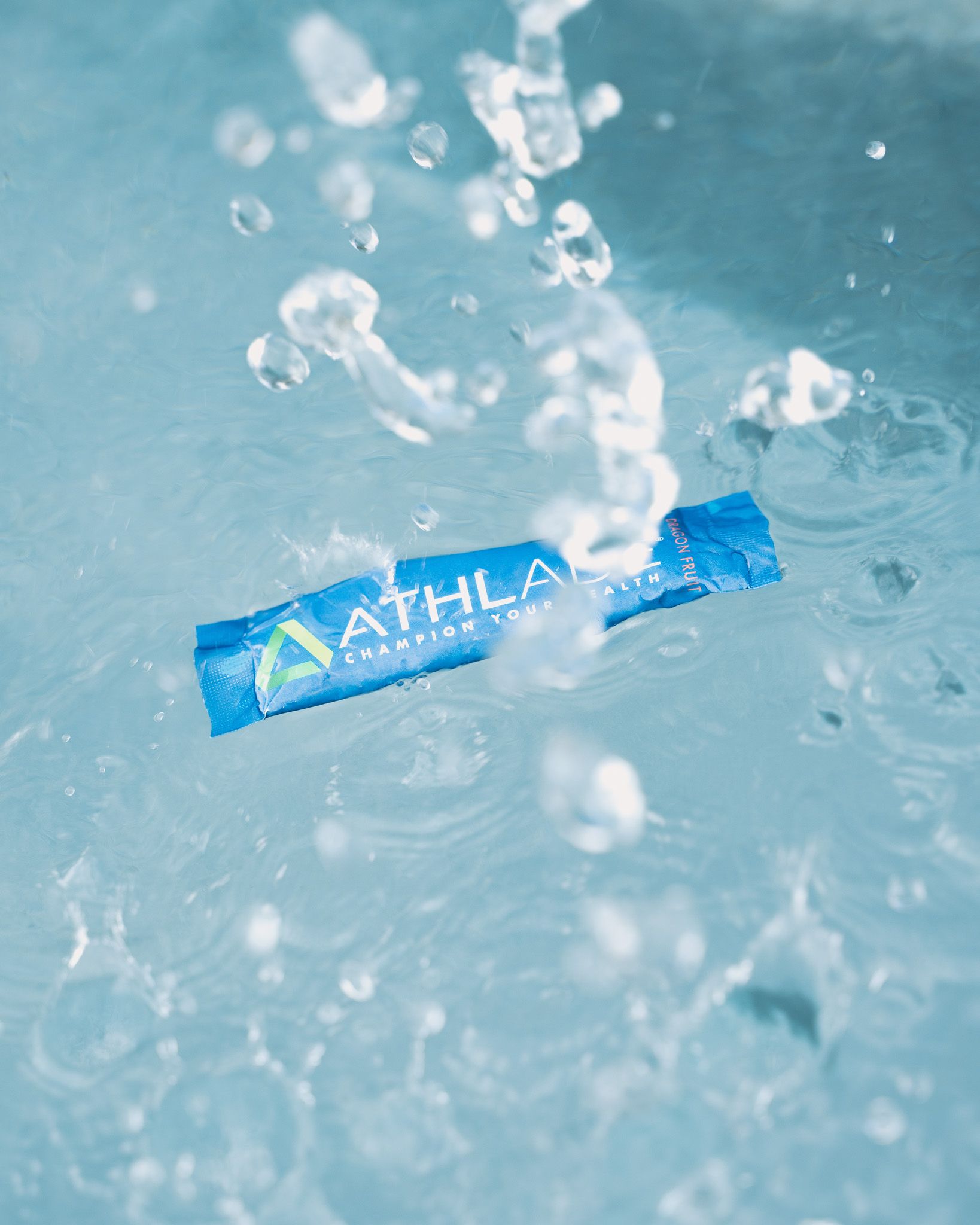 Blue Athlade wrapper splashing into clear water with droplets.