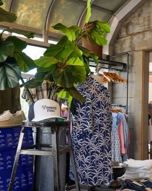 Retail display with white hat and clothing against leaf-decorated background.