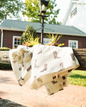 White decorative fabric with boot pattern hanging outdoors near lamp post.