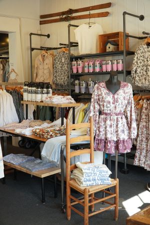 Boutique clothing store display with floral dresses and clothing racks against white walls.