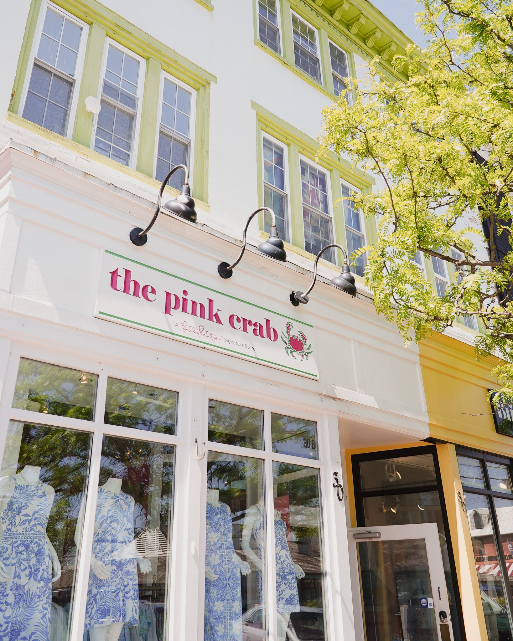 Exterior storefront of The Pink Crab boutique with green shuttered windows.