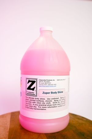 A gallon container of pink Z-Man Zuper Body Shine product on wooden surface.