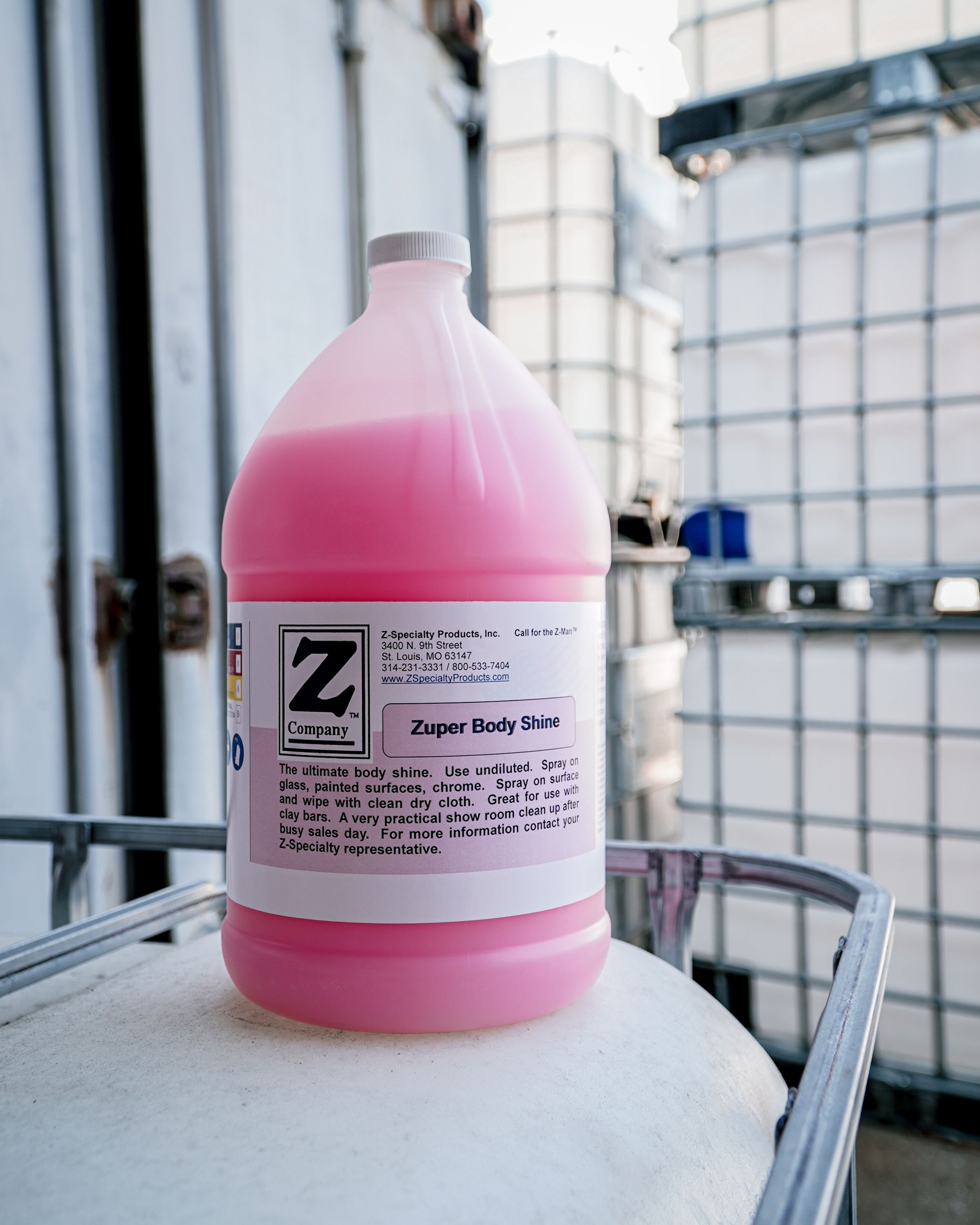 A pink gallon container of Super Body Sheen cleaner displayed against an industrial background.