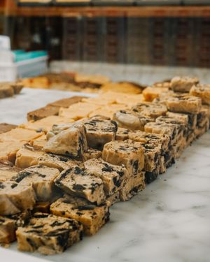 Close up of artisanal fudge pieces with chocolate swirls displayed on a marble counter.