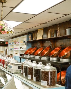 Vintage candy shop interior with glass jars of coffee beans and orange serving dishes on shelves.