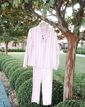 Pink and white striped pajama set hanging from tree branch in landscaped garden setting.