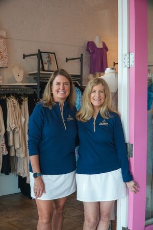 A retail clothing store interior with staff in matching navy uniforms.