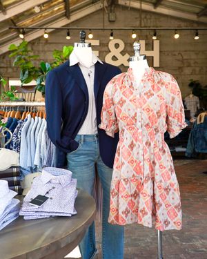 Navy blazer and coral floral dress displayed on mannequins in clothing store.