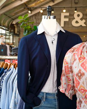 Navy blazer styled with light gray shirt and jeans on retail display.