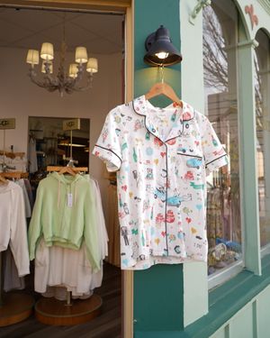 Storefront window display with whimsical printed pajama set and chandelier lighting.