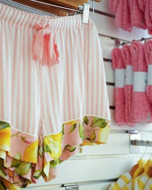 Pink and white striped pajama pants with ruffled hem detail hanging on retail display.