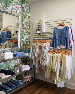 Boutique interior with blue and white clothing displayed on wall-mounted racks and shelving.