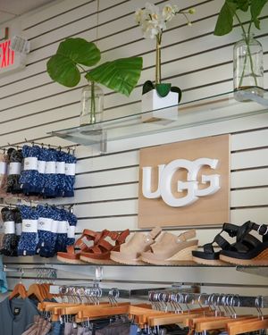 UGG store display featuring sandals and accessories with tropical leaf decor.
