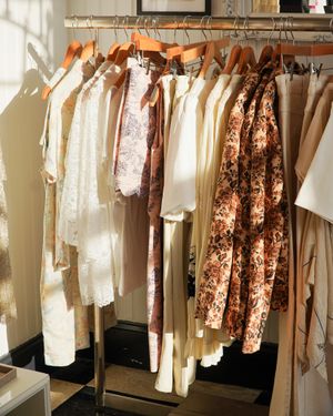 Cream and floral dresses hanging on wooden hangers in a bright retail space.