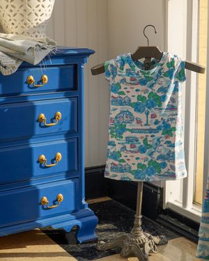 Blue vintage dresser with gold handles displayed next to a patterned children's t-shirt.