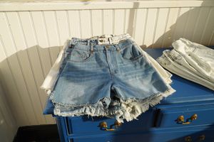 Distressed denim shorts displayed on a bright blue dresser.