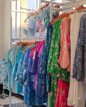 Colorful display of women's dresses and clothing on hanging racks in a boutique.