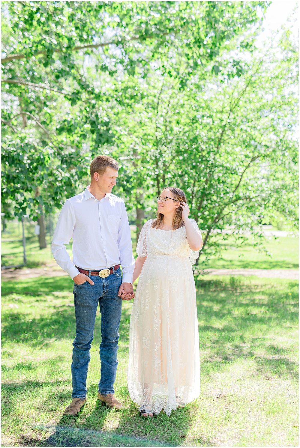 Joyful couple sharing sweet moment during outdoor maternity shoot among blooming spring trees.