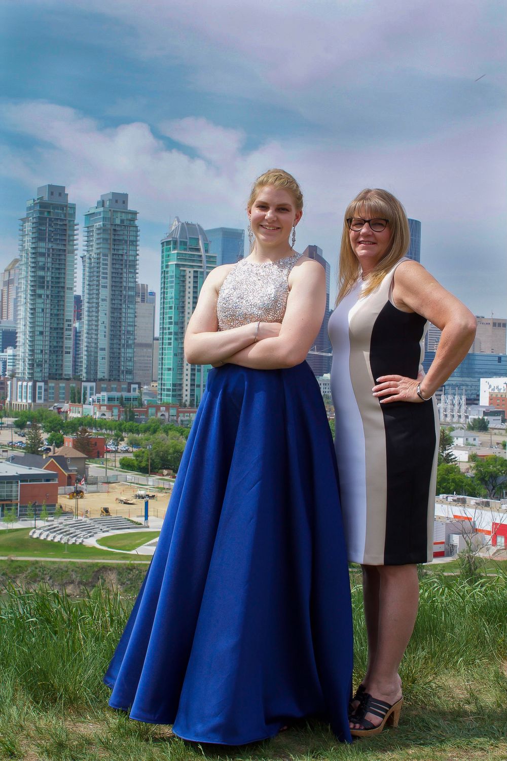 a grad stands with her mother with a big city skyline behind them.