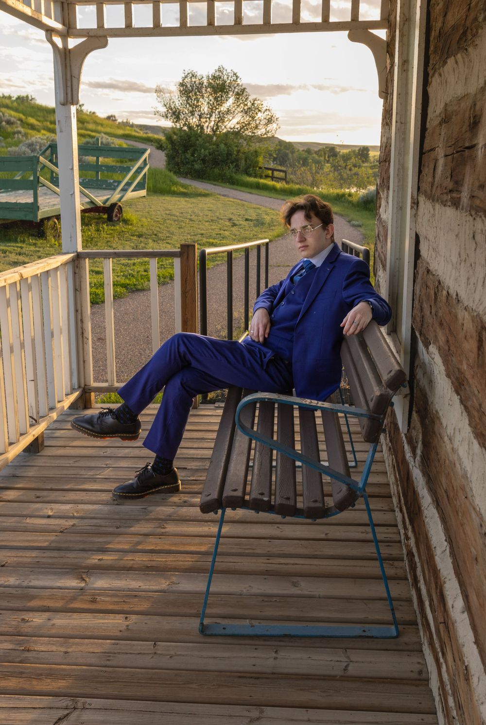 a grad in a suit on a bench on a porch.