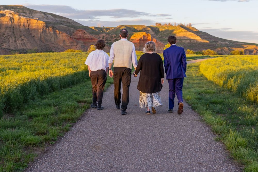 a grad and his family walk on a path, with red cliffs behind them.
