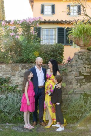 Family portrait in front of Mediterranean villa with yellow walls and flowering garden.